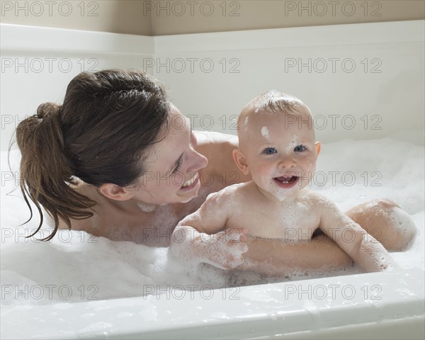 Mother and baby having bubble bath. Photographer: Mike Kemp