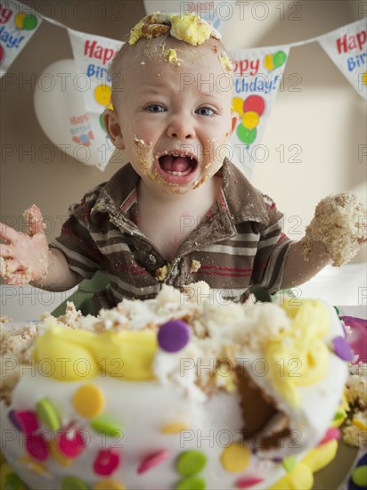 Baby covered in birthday cake. Photographer: Mike Kemp