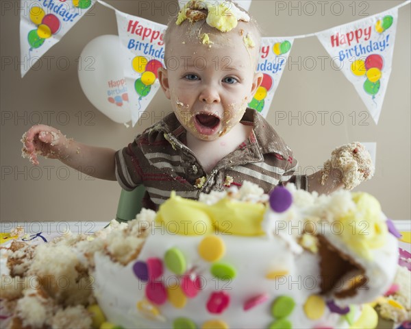 Baby covered in birthday cake. Photographer: Mike Kemp