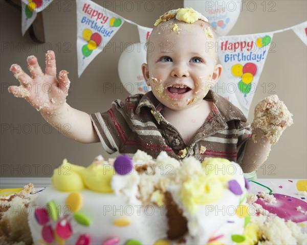 Baby covered in birthday cake. Photographer: Mike Kemp