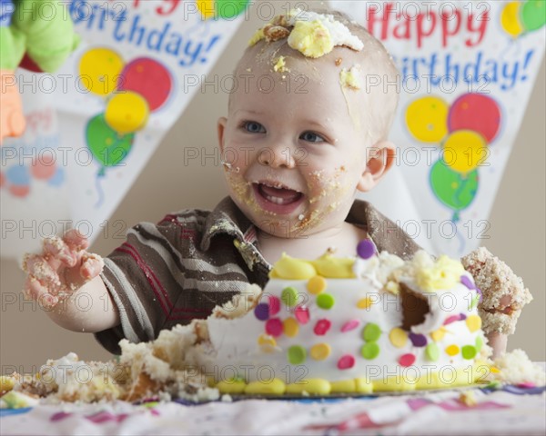 Baby covered in birthday cake. Photographer: Mike Kemp