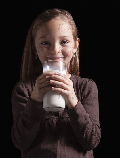 Young girl drinking glass of milk. Photographer: Mike Kemp