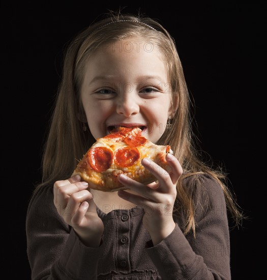 Young girl eating pizza. Photographer: Mike Kemp