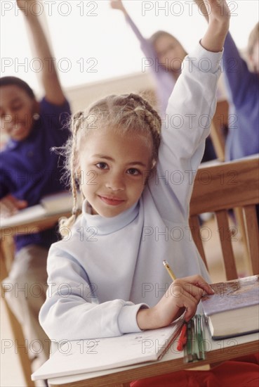 Students in classroom raising hands. Photographer: Rob Lewine