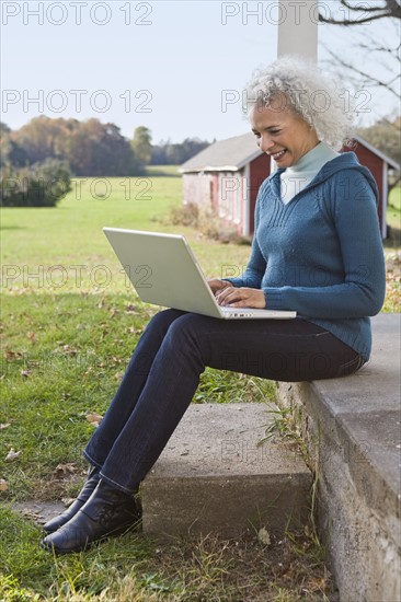 Woman working on laptop on porch. Photographer: Pauline St.Denis