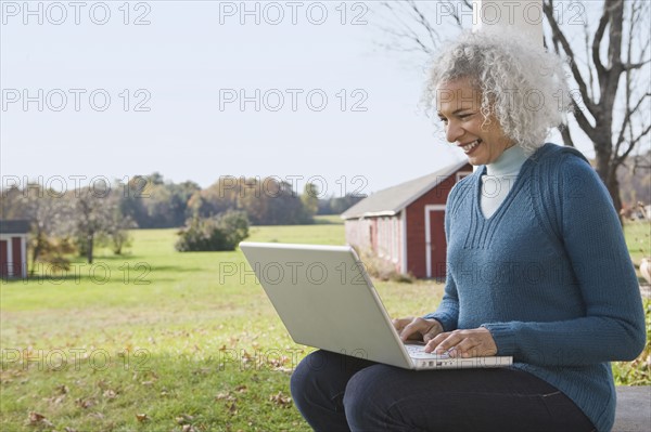 Woman working on laptop on porch. Photographer: Pauline St.Denis