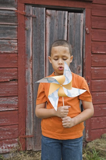 Boy blowing toy windmill. Photographer: Pauline St.Denis