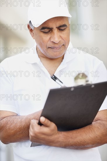 Tradesman writing on clipboard. Photographer: momentimages