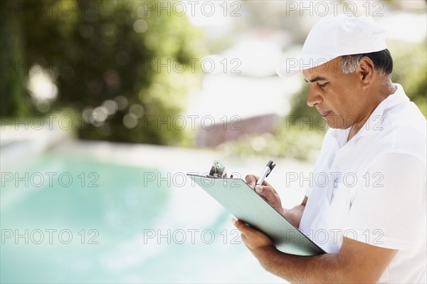 Tradesman writing on clipboard. Photographer: momentimages