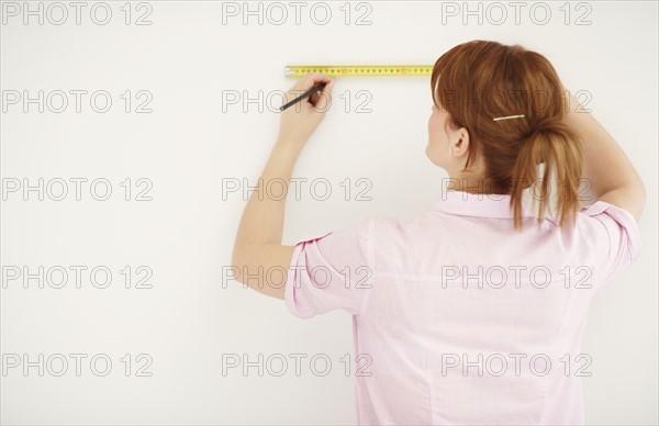 Woman using measuring tape. Photographer: momentimages