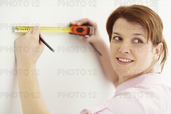 Woman using measuring tape. Photographer: momentimages