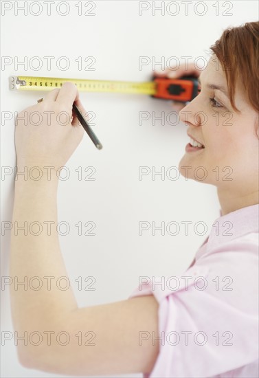 Woman using measuring tape. Photographer: momentimages