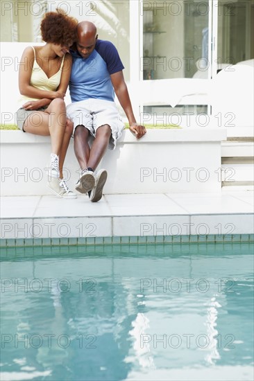 Couple sitting by pool. Photographer: momentimages