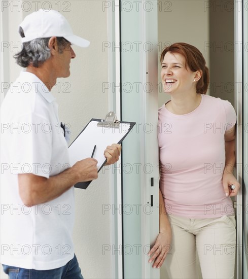 Woman talking to man at the door. Photographer: momentimages