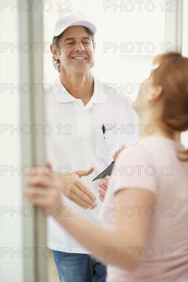 Woman talking to man at the door. Photographer: momentimages