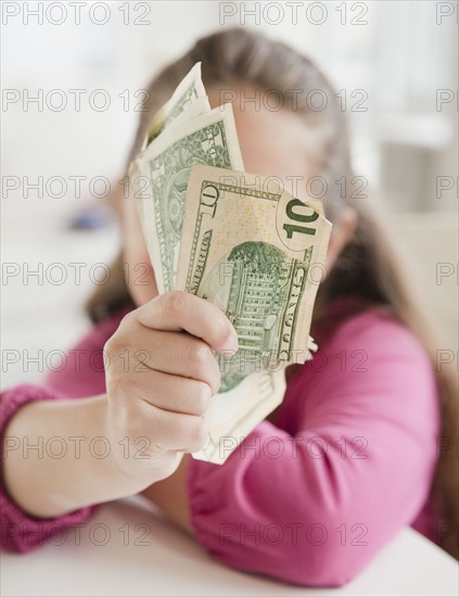 Young girl holding money. Photographer: Jamie Grill