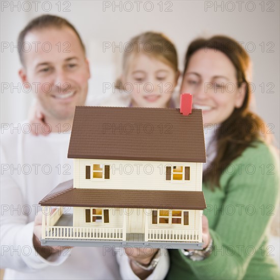 Family holding model house. Photographer: Jamie Grill
