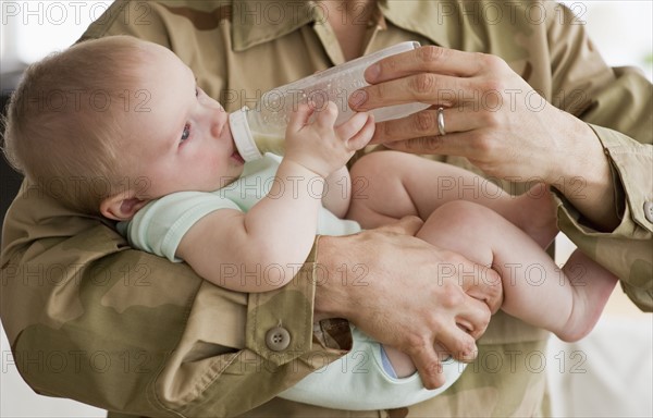 Soldier Feeding baby a bottle.