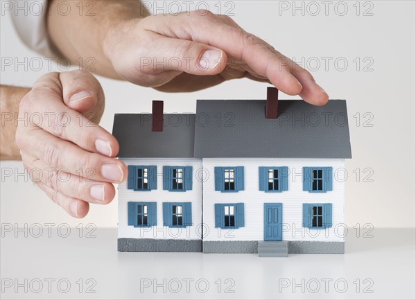 Hands touching toy house.