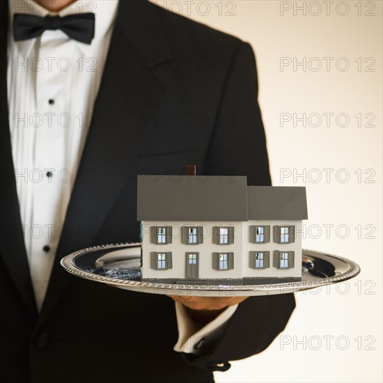 Butler holding toy house on tray.