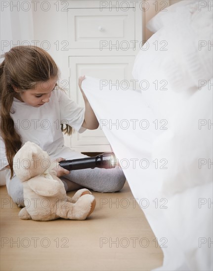 Young girl looking under bed. Photographer: Jamie Grill