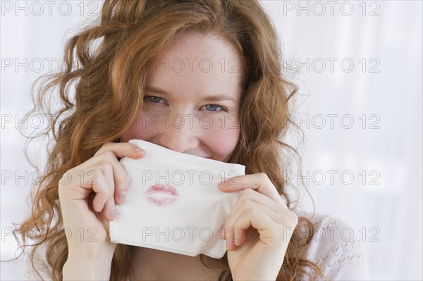 Woman holding tissue with lipstick on it.