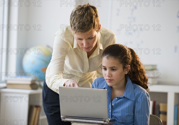 Teacher helping student in classroom.