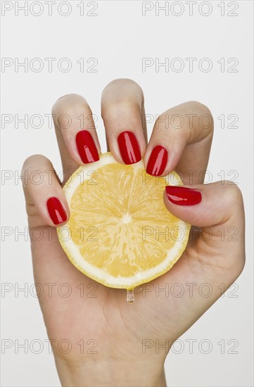 Hand holding slice of lemon.