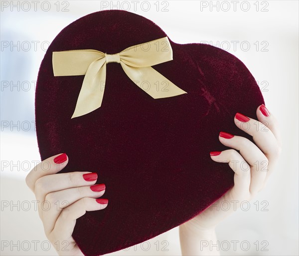 Hands holding a heart shaped box.