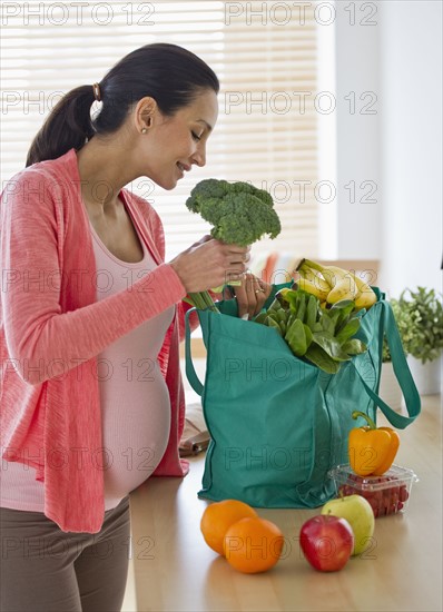 Pregnant woman unpacking groceries.