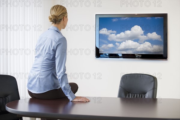 Businesswoman sitting on conference table.