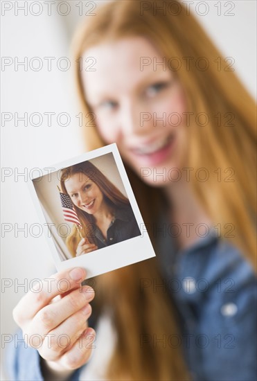 Woman holding photograph of herself.