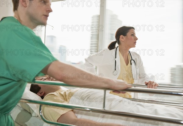 Healthcare workers pushing gurney in emergency room.