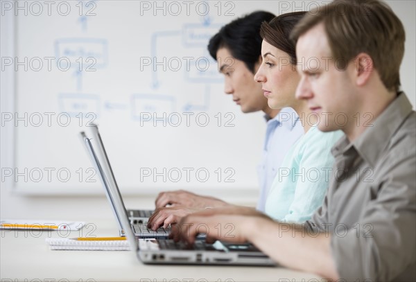 Adults working on laptops in classroom.