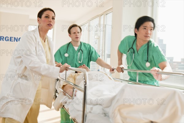 Healthcare workers pushing gurney in emergency room.