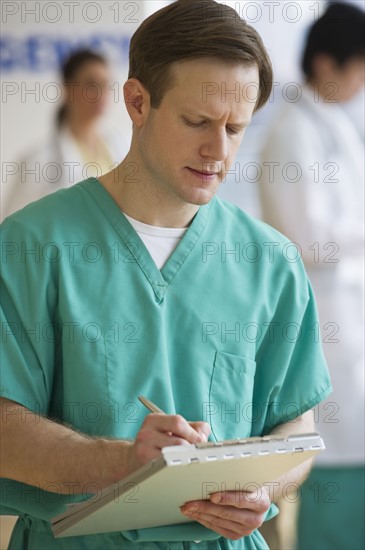 Doctor writing on chart.