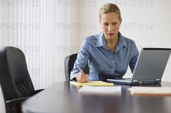 Businesswoman working at conference table.