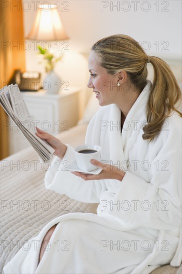 Woman drinking coffee in hotel room.