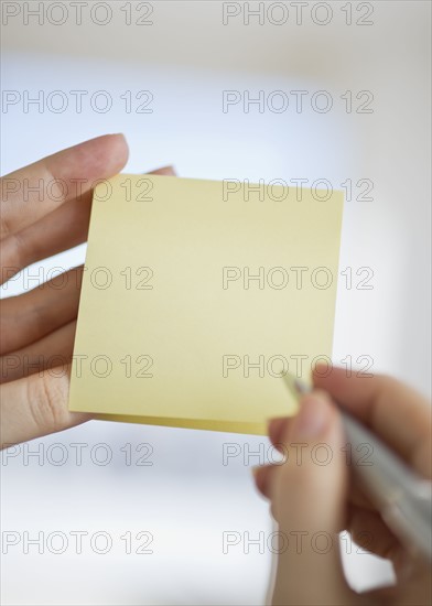 Hands holding notepad and pen.