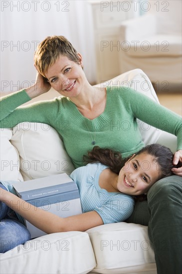 Mother and daughter relaxing on couch.