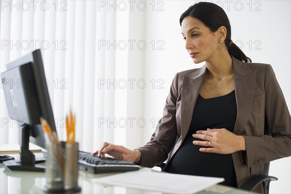 Pregnant businesswoman working on computer.