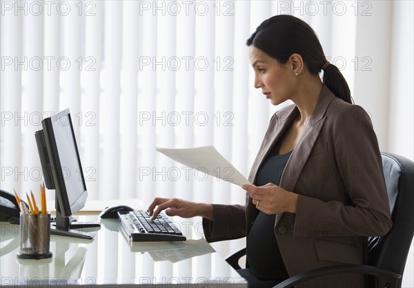 Pregnant businesswoman working on computer.