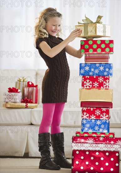 Young girl stacking Christmas gifts.