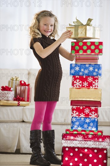 Young girl stacking Christmas gifts.