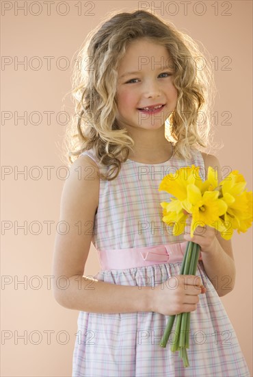 Young girl holding daffodils.