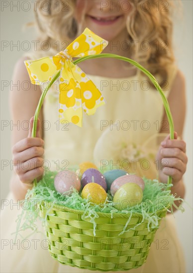 Young girl holding a basket of Easter eggs.