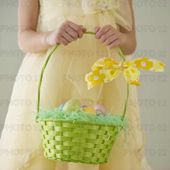 Young girl holding a basket of Easter eggs.