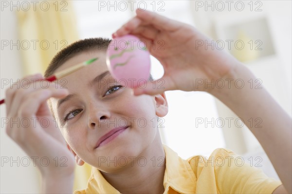 Young boy decorating an Easter egg.