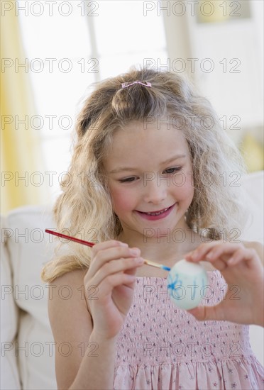 Young girl decorating an Easter egg.