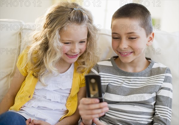 Siblings looking at cellular phone.